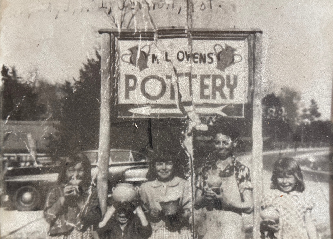 M.L. Owens Pottery sign with children holding pottery